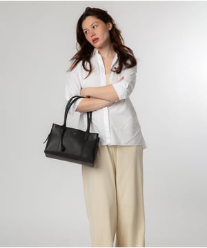 The 'Beatriz' handbag from NiNa Amora is crafted from natural leather with a soft to the touch pebble grain finish. This classic design is elevated thanks to the unique trio of main compartments. This comes in the form of a zipped central section with two magnetic press stud fastened slip pockets on either side; perfect for maintaining an organised accessory. Additional storage space is provided by slip pockets on the interior and exterior alongside a zipped pocket which lines the interior. Dual rounded leather handles adorn the bag with a drop length of 20cm. Silver coloured metal fittings and zips give this design a elegant look which pops against the leather exterior and complemented the NiNa Amora X logo which is silver foil embossed on the front and hanging charm for a luxurious finishing touch.