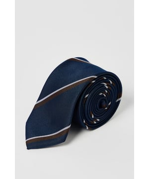 Classic navy tie featuring distinctive heritage diagonal stripes
        Standard width design suitable for both formal and smart-casual occasions
        Crafted with a smooth finish for easy knotting and a polished appearance
        Branded Burton label for authentic style credentials
        Machine washable at 30 degrees for convenient care
    
    This Burton Heritage Stripe Tie offers timeless British style with contemporary versatility. The diagonal stripe pattern presents a refined aesthetic that works brilliantly with a range of shirt options - pair with crisp white for important meetings or light blue for everyday office wear. The tie makes an excellent companion to a navy or grey suit for formal occasions, while also complementing more relaxed ensembles when worn with a blazer and chinos for family gatherings or weekend brunches. Perfect for the gentleman who appreciates classic styling with minimal fuss, this tie transitions seamlessly from daytime professional settings to casual evening drinks with colleagues. A wardrobe essential that reflects considered taste rather than fleeting trends - exactly what the modern British man requires from his accessories.