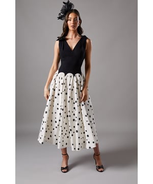 Elegant drop waist silhouette with contrasting bodice and skirt design
        Charming bow detail on shoulders adding a feminine touch
        Flattering V-neckline that frames the dcolletage beautifully
        Midi length skirt with playful polka dot pattern
        Sophisticated open back design for an alluring finish
    
    Make a striking impression at your next special occasion with this captivating Coast midi dress. The sophisticated drop waist design creates a flattering silhouette, whilst the contrast between the structured bodice and flowing skirt offers contemporary charm. The delicate bow shoulder details add a touch of whimsy to this otherwise refined piece. Style with strappy heeled sandals and a fascinator for race day sophistication, or pair with elegant court shoes and a clutch bag for wedding guest perfection. The versatile midi length works wonderfully for formal garden parties and evening receptions alike. For cooler weather, layer with a tailored blazer or a lightweight wrap to maintain the dress's graceful lines whilst staying comfortable throughout your event.