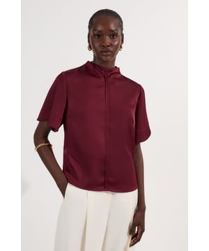 This Karen Millen satin top combines sophistication with everyday wearability. The boxy fit creates a modern silhouette that pairs with tailored trousers, or with your favourite denim for a high-low styling approach. The distinctive top stitching adds subtle interest to this versatile piece, making it perfect for daytime engagements. The high neckline offers a contemporary touch that works layered under a lightweight blazer. This top transitions effortlessly from office to weekend, making it a true wardrobe workhorse.  High neck design with distinctive top stitching detail Luxurious satin woven fabric Boxy silhouette Short sleeves Hidden front fastening