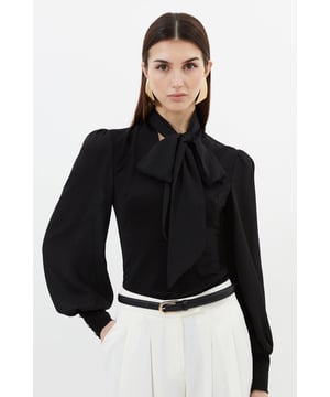 This Karen Millen bodysuit combines classic elegance with contemporary styling. The contrasting textures of jersey and georgette create visual interest, while the statement pussy bow adds a touch of feminine charm. The balloon sleeves provide dramatic volume balanced by the fitted bodice, creating a flattering silhouette. Perfect for family gatherings or casual work events, this bodysuit can be dressed down with tailored denim and flats for weekend brunches, or paired with a pencil skirt for more refined occasions. The secure bodysuit design eliminates the need for constant re-tucking, ensuring you maintain a sleek appearance throughout the day. A versatile wardrobe staple that offers both comfort and sophistication.  Jersey bodysuit featuring a georgette pussy bow detail Voluminous balloon sleeves with fitted cuffs and button detailing Round neckline Smooth, form-fitting designe