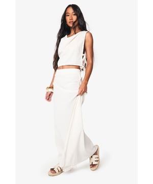 Elegant cowl neckline crop top with side tie detail for adjustable fit
        Linen-look fabric offers a breezy, textured appearance perfect for warm weather
        Sleeveless design with clean lines for effortless summer styling
        Coordinating A-line maxi skirt creates a sophisticated two-piece ensemble
        Flowing silhouette provides comfortable movement for beach days and holiday wear
    
    This striking two-piece set from Boohoo combines casual comfort with chic beach-ready style. The cowl neckline crop top drapes beautifully across the dcolletage, while the side ties allow for a customised fit to suit your shape. Paired with the sweeping A-line maxi skirt, this ensemble creates a flattering silhouette that moves gracefully with every step. Style with flat sandals and a woven beach bag as shown for daytime beachfront strolls, or dress up with metallic accessories and statement jewellery for sunset cocktails. The linen-look fabric offers that coveted holiday texture whilst remaining cool against the skin during hot summer days. Perfect for packing in your suitcase for Mediterranean getaways or simply lounging by the pool, this versatile co-ord will quickly become your warm-weather essential.