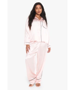 Luxurious satin finish with elegant contrast piping detail for a sophisticated nightwear look
        Classic button-through shirt design with notched collar and chest pocket for timeless appeal
        Long sleeves provide extra warmth and comfort during cooler evenings
        Relaxed fit trousers with wide legs ensure unrestricted movement whilst sleeping
        Plus size design specifically tailored to flatter and provide optimal comfort
    
    Transform your bedtime routine with this indulgent satin pyjama set from Boohoo. The contrast piping detail adds a touch of hotel-quality luxury to your nightwear collection, whilst the smooth fabric feels wonderfully soft against the skin. The traditional shirt silhouette features a smart notched collar and practical chest pocket, paired with generously cut trousers for ultimate comfort. Perfect for those cosy nights in when you fancy a bit of self-care - simply pair with your favourite slippers and a warm dressing gown for chillier evenings. This set also makes for a thoughtful gift or an essential addition to your weekend away wardrobe when you want to feel put-together even at bedtime. The versatile design works beautifully for both sleeping and lounging in style.