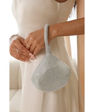 Add sparkle to your night with this Cascabel mini chainmail pouch bag, designed to dazzle at parties, weddings, or festive occasions. Its compact silhouette features shimmering crystal-style embellishments and a stylish knotted wristlet strap for easy carrying. Lightweight yet eye-catching, it's the perfect accessory for carrying your small essentials in glamorous style. A chic statement piece that blends retro charm with modern flair. Key Features: • Material: Rhinestone-embellished chainmail mesh • Dimensions: 16cm (L) x 14cm (H) x 10cm (W) • Fastening: Hidden zip closure at the top • Detail: Knotted wristlet strap for a secure and stylish hold