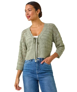 Textured Scallop Shrug from Roman. Add a touch of elegance to your outfit with this stunning scallop shrug, perfect for the Spring/Summer season. Crafted from textured tape yarn, this shrug features chic 3/4 sleeves and a soft hand touch for ultimate comfort. The scallop detailing adds a fun and stylish twist to the classic shrug style. Pair it with a simple t-shirt and jeans for a casual yet sophisticated look that can take you from day to night effortlessly.