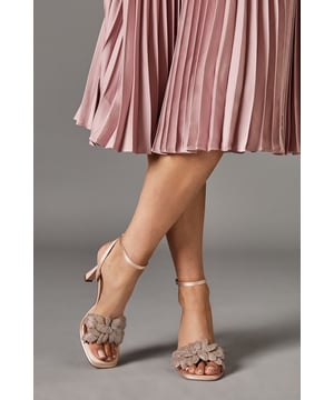 Luxurious satin finish with eye-catching diamante petal embellishment
        Elegant ankle strap with secure fastening for all-day comfort
        Sophisticated platform design adding extra height whilst maintaining stability
        Striking 8cm heel height perfect for special occasions
        Delicate floral-inspired detailing creating a feminine silhouette
    
    The Sandie Satin Diamante Petal High Heel Platform Sandals from Coast manifest sophistication with their stunning floral-inspired embellishment. These statement heels feature a secure ankle strap that ensures comfort throughout your celebration, whilst the platform design provides additional height without compromising on wearability. Style these elegant sandals with a flowing pleated dress as shown for a coordinated occasion ensemble that captures attention for all the right reasons. Perfect for weddings, race days or formal garden parties, these versatile heels will complement both contemporary and classic outfits. The diamante detailing catches the light beautifully as you move, adding a touch of glamour to your special event attire. These sandals are designed to be the finishing touch to your most memorable moments, offering both style and comfort when you need to look your absolute best.
