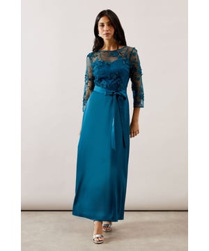 Elegant maxi dress featuring delicate mesh overlay with intricate embroidered detailing
        Sophisticated crew neckline and three-quarter length sheer sleeves for refined coverage
        Flattering satin skirt that flows gracefully to a maxi length
        Feminine waist tie belt to accentuate your silhouette
        Stunning illusion effect created by the contrast between the mesh bodice and lined underskirt
    
    This enchanting Wallis occasion dress combines the luxurious feel of satin with the delicate beauty of embroidered mesh for a truly sophisticated ensemble. The sheer overlay across the bodice and sleeves creates a captivating illusion effect, whilst the flowing maxi skirt offers graceful movement as you walk. Perfect for weddings, formal dinners or race day events, this dress radiates timeless elegance. Style with metallic strappy heels and a coordinating clutch for classic sophistication. For cooler evenings, layer with a tailored cropped jacket or elegant pashmina. Complete your look with understated jewellery, such as the delicate drop earrings shown, to maintain the dress's refined aesthetic whilst allowing the exquisite embroidery detail to remain the focal point of your ensemble.