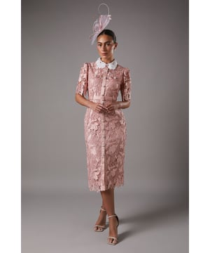 Exquisite lace overlay with intricate floral pattern
        Contrasting white collar for a striking visual effect
        Elegant midi length with a sophisticated side slit
        Short puff sleeves with delicate scalloped edges
        Button-down front for a classic shirt dress silhouette
    
    This stunning lace shirt dress from Coast is the epitome of refined elegance. The intricate floral lace overlay creates a captivating visual texture, while the contrasting white collar adds a touch of sophistication. Perfect for formal occasions, this dress can be styled with strappy heels and statement earrings for a wedding or the races. The midi length and side slit offer a flattering silhouette, allowing for graceful movement. For a more versatile look, pair it with pointed-toe court shoes and a clutch bag for an evening soire. The button-down front and collared neckline give a nod to classic tailoring, making this dress a timeless addition to your occasion wear collection. Whether you're attending a graduation ceremony or a garden party, this Coast dress will ensure you stand out with its blend of traditional charm and contemporary allure.