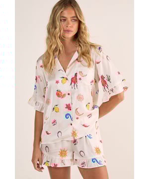 Luxurious satin finish with playful western-inspired conversational print featuring fruits, suns, and desert motifs
        Relaxed button-up short sleeve top with charming ruffle trim detailing
        Matching shorts with ruffle hem for a coordinated nightwear look
        Comfortable loose fit designed for ease of movement during sleep
        Collared neckline with classic front button closure for adjustable styling
    
    Drift into dreamland with this delightfully whimsical Satin Western Conversational Ruffle Pajama Shorts Set from Nasty Gal. The charming print showcases a playful array of western-inspired motifs, creating a fun yet sophisticated nightwear option. The relaxed silhouette features a button-up top with short sleeves and a classic collar, whilst the coordinating shorts offer the perfect balance of comfort and style. The ruffle detailing adds a feminine touch to this set, making bedtime feel that little bit more special. Perfect for warm summer evenings or cosy nights in, this set can be worn whilst lounging with a good book and a cup of tea, or for those lazy weekend mornings when breakfast in bed is calling. For chillier nights, simply pair with fluffy socks and a lightweight dressing gown for additional warmth without compromising on style.