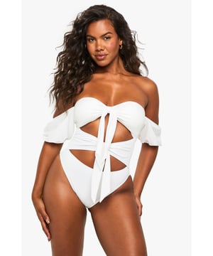 Elegant tanga swimsuit designed specifically for bridal occasions
        Striking off-shoulder design with delicate puff sleeves for a romantic touch
        Distinctive front bow detail creating a sophisticated cut-out effect
        High-cut leg design for an elongating silhouette
        Flattering high-waisted back for comfortable coverage
    
    Make a statement on your special day with this show-stopping bridal tanga swimsuit from Boohoo. Perfect for honeymoon beach days or pre-wedding poolside celebrations, this distinctive piece combines contemporary design with bridal elegance. The charming off-shoulder style with soft puff sleeves creates a feminine silhouette, whilst the decorative bow detailing and strategic cut-outs add a modern twist to traditional bridal swimwear. The high-cut leg design elongates your figure beautifully, whilst the high-waisted back ensures you feel confident and comfortable throughout your celebration. Pair with oversized sunglasses and a flowing kimono for poolside glamour, or style with a sheer sarong and delicate anklet for beachside sophistication. This swimsuit transitions effortlessly from daytime sunbathing to sunset cocktails, ensuring you look and feel fabulous throughout your bridal celebrations.