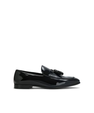 The KG Kurt Geiger Curtis is a patent slip on loafer. It is crafted from a black patent leather with two tassel details across the elongated vamp.