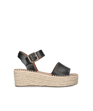 The Pia sandal arrives with a black upper that is tied with a gold buckle. The platform heel features a rope espadrille detail with platform toe detail. The sole sits at 7.5cm. This product is registered with The Vegan Society.