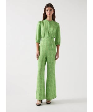 The Naomi jumpsuit features swirling abstract prints on a green satin crepe canvas. This  design includes neck and cuff frills, complemented by ball self-covered buttons with rouleau loops, made from viscose. Ideal for glamorous evenings, pair it with sleek heels and statement earrings for an unforgettable look.