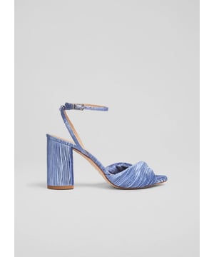 The Lilith twist front sandals in serene blue feature a textured cotton blend upper, leather lining, and a stylish block heel. They are perfect for weddings or special nights out. Pair with an evening gown or tailored trousers for a striking look.