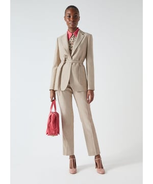 Revealing the Amelia jacket, crafted in Portugal with luxurious fabric and adorned with flat gold metal buttons. This beige, single-breasted jacket features a cinch tie waist and functional front pockets, offering a flattering silhouette for workwear elegance. Ideal for important meetings or a polished workday look. Style it with tailored trousers and a sleek blouse for a refined office ensemble.
