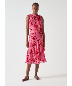 The Rhoda wildflower tiered skirt captures the charm of an enchanted garden. Its captivating pink floral print on luxurious viscose georgette fabric adds an air of elegance. The midi design features peplum layered tiers and a concealed side zip, ensuring a seamless look. Perfect for special occasions, this skirt pairs beautifully with a delicate blouse or a sleek evening top.