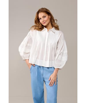 De witte Alice blouse met plooien wordt gegarandeerd je nieuwe favoriet! Deze luchtige, witte katoenen blouse komt in een trendy nieuw ontwerp. Wat deze blouse echt uniek maakt, zijn de bijzondere plooidetails. Met een rechte, oversized pasvorm en elegante pofmouwen is deze blouse perfect voor verschillende looks. De voorkant is voorzien van verfijnde verticale plooien, terwijl de horizontale plooien op de mouwen een speelse twist geven. De blouse heeft een klassieke kraag en een blinde knoopsluiting. De mogelijkheden om deze korte blouse te combineren zijn eindeloos. Combineer hem met een denim broek voor een casual chique uitstraling of, voor een zakelijke look, draag hem met de Torya broek en een paar hakken voor een stijlvolle en zelfverzekerde indruk. De Alice blouse is beschikbaar in de tijdloze kleuren wit en zwart, waardoor het een klassieke toevoeging is aan je garderobe, met oog voor detail.