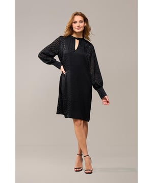 Kies dit seizoen voor de Abilene-jurk in klassiek zwart. Deze stijlvolle jurk combineert moeiteloos elegantie en comfort met een prachtig glanzend stippenmotief op een semi-transparante stof. Het ontwerp is voorzien van een opstaande kraag en subtiele keyhole-openingen aan de voor- en achterkant, wat zorgt voor een verfijnde en unieke uitstraling. De lange ballonmouwen en brede manchetten voegen een modieuze touch toe, terwijl de knie-lengte en ruimvallende pasvorm garant staan voor draaggemak. Het glanzende stippenmotief geeft de jurk een luxe designer-look en maakt het een echte blikvanger. Combineer de jurk overdag met stoere boots en een denim jack voor een casual-chique outfit, of draag haar 's avonds met elegante hakken voor een zomerse dinerdate of een gezellige avondborrel. Met een ceintuur kun je een flatterend zandloperfiguur creëren, maar de jurk kan ook comfortabel los worden gedragen. Fashiontip: Ontdek ook de groene versie van deze jurk of kies voor de stijlvolle zwarte blouse met hetzelfde speelse stippenmotief!