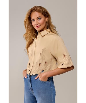 De Tirzy blouse in zand is een must-have voor een elegante en luchtige uitstraling. Dit verfijnde ontwerp uit de nieuwste collectie van Mart Visser straalt stijl uit dankzij de subtiele borduurseldetails langs de mouwen en zoom. Deze delicate accenten geven de blouse een speels en toch chic karakter, waardoor het een veelzijdige toevoeging is aan je garderobe. De doorknoopsluiting aan de voorkant zorgt voor een tijdloze, klassieke touch, terwijl de kortere snit op de heup een modern en flatterend silhouet creëert. De blouse is vervaardigd uit een ademende mix van polyester en katoen, wat zorgt voor een licht en comfortabel draaggevoel – ideaal voor warmere dagen.