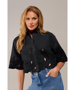 De Tirzy blouse in zwart is een tijdloze must-have voor wie elegantie en eenvoud wil combineren. De subtiele borduurseldetails op de mouwen en zoom geven de blouse een verfijnde en speelse touch. Dankzij de doorknoopsluiting aan de voorkant behoudt het ontwerp zijn klassieke charme, terwijl de kortere snit net boven de heup zorgt voor een moderne en flatterende pasvorm. Gemaakt van een lichte en ademende mix van polyester en katoen, is deze blouse ideaal voor zowel formele als casual gelegenheden.