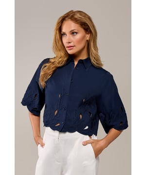 De Tirzy blouse in navy is een stijlvolle must-have die je garderobe compleet maakt! Met verfijnde borduursels langs de mouwen en zoom straalt deze blouse elegantie uit. De doorknoopsluiting aan de voorkant zorgt voor een klassieke touch, terwijl de kort vallende snit op de heup een modern en flatterend effect geeft. Dankzij de combinatie van ademend polyester en katoen voelt de blouse licht en comfortabel aan, ideaal om het hele jaar door te dragen. Of je nu kiest voor een chique zakelijke look of een casual outfit, deze navy blouse past moeiteloos bij elke gelegenheid.