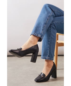 Sophisticated loafer design with decorative metal bar detail across the front
        Generous wide fit for all-day comfort in the office
        Sturdy high block heel measuring between 7-9cm for elegant height
        Smooth faux leather finish that pairs beautifully with workwear
        Classic square toe silhouette offering timeless appeal and extra room
    
    These Lucky High Block Heeled Loafers from Wallis strike the perfect balance between sophistication and practicality for the modern professional. The generous wide fit ensures comfort throughout your busy workday, whilst the substantial block heel provides stability without sacrificing style. Pair these versatile loafers with tailored trousers as shown for a polished office ensemble, or style with a pencil skirt and crisp blouse for important meetings. The sleek design transitions effortlessly from day to evening, making them ideal for after-work gatherings. The decorative metal bar adds just the right touch of glamour to complement your most refined outfits, whilst the square toe offers contemporary flair. These loafers will quickly become your go-to footwear choice when you need to project confidence and sophistication in the workplace.
