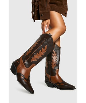 Wide fit design ensures all-day comfort for various foot widths
        Striking contrast leaf embroidery detail adds distinctive western flair
        Low heel height of 2.5-4.5cm offers practical elevation without sacrificing comfort
        Classic pointed toe and western-inspired silhouette for authentic cowboy boot styling
        Two-tone colour blocking creates visual interest and versatile styling options
    
    Channel your inner cowgirl with these statement western cowboy boots, designed with comfort in mind. The wide fit construction ensures these boots accommodate various foot widths whilst maintaining their striking silhouette. The distinctive leaf embroidery creates a bold contrast against the two-tone design, whilst the practical low heel offers just the right amount of elevation for everyday wear. Perfect for festival season paired with denim shorts and an oversized shirt, or style with a floaty midi dress for a contemporary countryside look. These versatile boots transition effortlessly from casual daytime outings to evening gatherings. For autumn, wear with straight-leg jeans and a chunky knit jumper for an on-trend ensemble that combines practicality with western-inspired fashion. These Boohoo boots are the ideal finishing touch to countless outfits throughout the year.