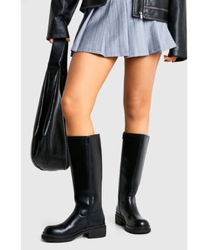Sleek knee-high design with a robust column silhouette
        Chunky, durable sole with a comfortable low heel (3.5cm)
        Smooth finish with minimal seam detailing for a contemporary look
        Rounded toe shape offering all-day comfort
        Versatile pull-on style with a structured shaft that holds its shape
    
    These statement knee-high boots combine practicality with fashion-forward design, perfect for the style-conscious woman who doesn't compromise on comfort. The chunky column silhouette creates a bold profile that pairs brilliantly with mini skirts and pleated styles as shown, or works equally well with skinny jeans tucked in for a streamlined look. The low heel ensures these boots are ideal for all-day wear, whether you're navigating city streets or meeting friends for weekend brunches. Their clean, minimalist aesthetic makes them incredibly versatile for casual styling throughout the cooler months. Layer with oversized knitwear and a leather jacket for an effortlessly cool autumn ensemble, or pair with a midi dress and tights when temperatures drop. These boots offer the perfect balance of edgy style and everyday wearability that's signature to the Boohoo aesthetic.