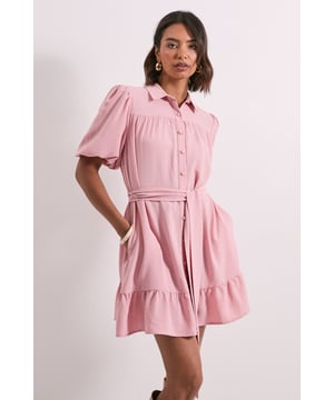 Charming mini shirt dress with elegant puff sleeves for a feminine silhouette
        Flattering belted waist design to accentuate your figure
        Button-through front styling for versatile wear options
        Delightful ruffle hem detail adding playful movement
        Classic collar neckline offering a smart-casual finish
    
    This delightful puff sleeve mini shirt dress from Dorothy Perkins strikes the perfect balance between casual comfort and put-together style. The gathered detailing at the shoulders creates a soft, feminine shape while the included belt cinches the waist beautifully for a flattering silhouette. Style with knee-high boots for a chic daytime look that's perfect for weekend brunches with the girls or family gatherings. For a more relaxed approach, pair with white trainers and a denim jacket. The button-through design allows for versatile styling options, while the playful ruffle hem adds movement and charm. This dress transitions effortlessly from casual coffee dates to baby showers - simply switch up your accessories to suit the occasion. A wardrobe essential that combines practicality with on-trend details.