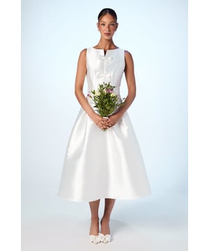 Elegant midi dress featuring three decorative bow details along the bodice front
        Sophisticated notch neckline adding a refined touch to the sleeveless design
        Structured full skirt creating a dramatic silhouette with generous volume
        Flattering fitted bodice contrasting beautifully with the voluminous skirt
        Midi length falling gracefully below the knee for a timeless occasion look
    
    This striking bow detail midi dress presents the perfect canvas for your most important occasions. The classic silhouette combines a fitted bodice with a gloriously full skirt that creates movement with every step, whilst the trio of bows adds distinctive character to this refined piece. Style with statement earrings as shown and elegant heeled sandals for weddings or race day events. For cooler weather, layer with a tailored cropped jacket and clutch bag. The notch neckline frames the dcolletage beautifully, making this the ideal backdrop for your favourite jewellery. This versatile dress transitions effortlessly from daytime celebrations to evening affairs-simply switch your accessories to reflect the changing atmosphere of your event.