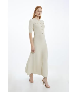 Elevate your evening wardrobe in our midaxi dress, with a figure hugging bodice that flares into a long skirt, and metallic hardware. Style it with heels, loafers, or sandals for an evening look perfect for occasions that require something a little extra. Rib Knit Military Trim Midaxi Dress High Quality Ribbed Knit Fabric Metallic Button Detailing High, Round Neckline Three Quarter Length Sleeves Flattering Fit and Flare Silhouette