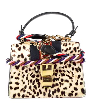 VINTAGE, RRP AS NEW
The Gucci Mini Sylvie Leopard Print Top Handle Bag in beige pony hair combines vintage-inspired elegance with bold, modern flair. Featuring the iconic Sylvie web stripe and gold chain detail, this compact statement piece brings a luxurious touch to any outfit. **Style tip:** Let the bag stand out by styling it with neutral tones and sleek silhouettes—think a cream blouse, tailored trousers, and classic loafers.

 Gucci Mini Sylvie Leopard Print Top Handle Bag in Beige Pony Hair

Condition: Excellent
Signs of wear: No retail tag, No visible sign of wear., 
Packaging: None
Color: Beige
Material: Pony hair wool
Size: One Size | One Size
Measurements: Width: 60; Height: 140; Length: 200
SKU: NAPPUGBBA524380W