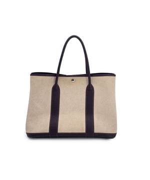 VINTAGE, RRP AS NEW
This beautiful Bag will come with a Certificate of ity provided by Entrupy, leading International Fashion ators. The certificate will be provided at no further cost  There's something effortlessly timeless about the Hermès Garden Party 36-a model that balances understated elegance with everyday practicality. This particular piece, crafted in 2007 (date code: K in a square), is a beautiful example of the house's mastery of casual luxury.  Its beige canvas, subtly woven from two tones of thread, offers a tactile depth that feels both relaxed and refined. The dark brown leather trim and dual rolled handles ground the bag with classic structure, while the palladium 'Clou de Selle' snap button closure and expandable sides make it adaptable for daily use. Inside, the embossed "Hermès Paris - Made in France" stamp on the leather trim is a quiet nod to the heritage and craftsmanship behind the piece.  Whether carried to the market or tucked under your arm for a countryside weekend, the Garden Party 36 proves that true luxury lives in the Condition Rating: B - VERY GOOD CONDITIONCondition Details: Gently used. Some darkness on canvas on the side due to normal use. Some normal wear of use on bottom coners. Some pen marks inside. Please check the photos carefully and ask if you need to know more details or if you have any doubts.Measurements (cm):Depth: 16.5Height: 24.1Length: 36.8Other Details: Dustbag? NoKeys? NoBox? No Measurments:  width: 165 mm length: 368 mm height: 241 mm