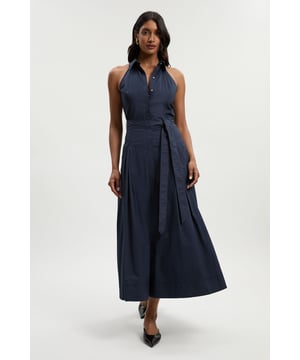 This Karen Millen cotton shirt dress combines timeless elegance with contemporary design. The collared halter neckline creates a refined frame for your decolletage, while the dropped waist and flowing midi skirt offer a flattering silhouette for various body types. Perfect for summer garden parties or sophisticated brunches, this dress can be styled with flat sandals as seen on our model for a relaxed daytime look. For cooler evenings, layer with a lightweight cardigan and accessorise with delicate jewellery to enhance its feminine charm. The versatile design transitions effortlessly from casual weekend outings to family gatherings; simply switch your footwear from sandals to ballet flats and add a structured handbag to reflect your personal style. The cotton construction ensures all-day comfort, making this a wardrobe essential for the warmer months.  Elegant halter neck design with crisp collar detail for a sophisticated silhouette Flattering dropped waist construction that creates a beautiful flowing shape Woven cotton fabric offering breathable comfort throughout the day Full midi-length skirt with generous pleating for graceful movement Versatile tie detail at the waist that can be styled to preference