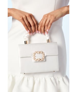 Luxurious satin finish with elegant pearl and jewel embellished brooch closure
        Structured top handle design with detachable chain strap for versatile wearing options
        Compact yet practical interior with dedicated card slots
        Secure magnetic fastening to keep your essentials safe
        Gold-tone hardware accents for a sophisticated finishing touch
    
    Make a graceful statement on your special day with this exquisite grab bag from Coast. The lustrous satin finish creates a refined canvas for the stunning pearl and jewel brooch detail that adorns the front. Designed with versatility in mind, carry it by the structured top handle for a formal look, or attach the delicate chain strap for hands-free elegance. The compact silhouette houses just enough space for your wedding day essentials whilst maintaining a sleek profile. Perfect for complementing your bridal ensemble, this bag also transitions beautifully to other milestone celebrations. Style with a fitted dress and heels for a sophisticated wedding guest look, or pair with a tailored jumpsuit for elegant evening affairs. This timeless accessory will become a cherished keepsake long after your celebration.