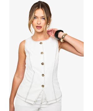 Sleek bandeau waistcoat featuring eye-catching gold buttons for a luxe finish
        Distinctive contrast stitching detail that adds visual interest and dimension
        Figure-flattering regular fit with structured seaming for a polished silhouette
        Versatile sleeveless design perfect for layering or wearing as a standalone piece
        Tailored shape with a subtle peplum effect at the waist for added definition
    
    Make a statement with this contemporary waistcoat that combines classic tailoring with modern details. The striking contrast stitching and gleaming gold buttons transform this piece from simple to standout, whilst the structured fit creates a flattering shape that works for various body types. Style with matching wide-leg trousers for a coordinated ensemble that's perfect for brunches or casual gatherings. For everyday wear, pair with your favourite denim and trainers for an effortlessly chic look. When the evening calls for something more refined, layer over a crisp shirt with tailored trousers and heels. This versatile waistcoat transitions seamlessly from day to night, making it an essential addition to your wardrobe that offers countless styling possibilities throughout the seasons.