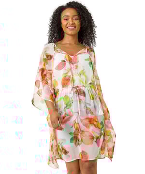 Petite Abstract Print Tie Cover Up from Roman. Get ready to bloom this Spring Summer in this Petite abstract print cover up. Featuring a classic round neckline with a cute tie front detail and short sleeves, this piece is crafted from a comfy woven fabric and adorned with a charming abstract floral print. The tie waist detail adds a touch of shape to the loose fit. For the perfect beach look, style with a Summer bag and wedged heels!