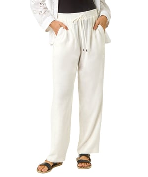 Full Length Linen Trouser from Roman. Stay cool and comfortable this Spring and Summer in these chic full-length linen trousers. Crafted from a breathable linen fabric, these trousers offer a relaxed and flowy fit. Perfect for warm weather, these tie front trousers feature a simple yet elegant design that can be dressed up or down effortlessly. Pair with a stylish cami top and sandals for a laid-back and fashionable look that is perfect for any casual occasion.