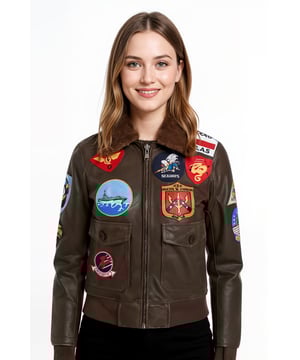 Inspirada en la icónica película de 1986, esta chaqueta de aviador Top Gun para mujer combina un estilo militar vintage con un corte femenino. Confeccionada en cuero genuino y adornada con 17 parches auténticos, está disponible en dos acabados: negro clásico y marrón envejecido, para una declaración audaz y atemporal. Características principales: Cuero genuino de vaca: material duradero y de alta calidad. 17 parches con precisión de pantalla: incluye un pin de ancla de la USN. Ajuste a medida: diseñado para mujer. Cuello de piel de oveja: marrón rojizo o negro, estilo bomber de los años 60. Bolsillos funcionales: solapa exterior y compartimento interior. Estilo cinematográfico: inspirado en la película Top Gun. Pieza de coleccionista: ideal tanto para fans como para amantes de la moda.