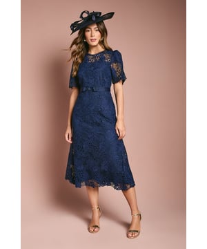 Exquisite lace midi dress with intricate floral pattern
        Elegant bow belt accentuates the waistline
        Flattering round neckline and short sleeves
        Scalloped hem adds a delicate touch
        Midi length perfect for formal occasions
    
    This stunning lace midi dress radiates sophistication and grace, making it an ideal choice for weddings, races, or any formal event where you want to make a lasting impression. The intricate floral lace pattern adorns the entire dress, creating a romantic and feminine silhouette. The bow belt cinches the waist beautifully, enhancing your figure and adding a charming detail. Style this dress with a matching fascinator, as shown, for a coordinated look that's sure to turn heads. Pair with strappy metallic heels and a clutch bag to complete your ensemble. For cooler evenings, drape a lightweight pashmina over your shoulders. This versatile piece can be dressed up or down, making it a valuable addition to your occasion wear wardrobe.