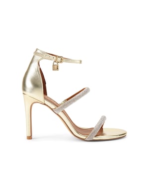 This Kurt Geiger Park Lane heel is crafted from a gold leather. The heel is enclosed with gold buckle on the ankle strap as well as small gold branded stud detail at the heel. Heel height: 9.5cm.