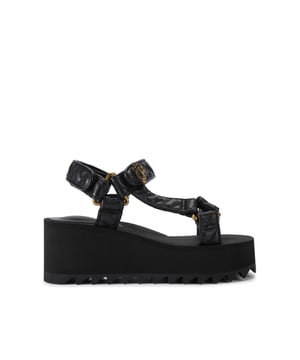 This Kurt Geiger Orion Pump sandal sits on a chunky black sole with exaggerated tread. The upper is in a black overstitch quilted leather alternative. The straps are fastened with velcro topped with an antiqued brass eagle head. Sole height: 7cm.