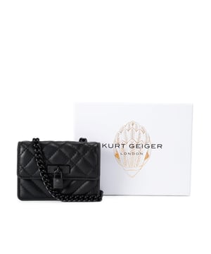 This Kurt Geiger Micro Drench Brixton bag features a black leather alternative exterior with overstitch quilting on the exterior. There is an antiqued brass branded lock on the front flap. Dimensions: 7.5cm (H), 11cm (L), 3cm (D). Strap length: 121cm.