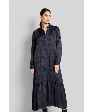Dieses Blusenkleid ist aus 100 % fließender und weicher Viskose gefertigt. Die grafischen Prints sowie der moderne Stehkragen setzen ein Statement. Das Kleid mit Volant hat eine verdeckte Knopfleiste und feminine Raffungen im Schulterbereich und an der Ärmelmanschette.