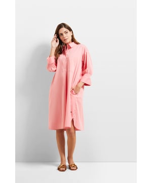 Das lockere Hemdblusenkleid mit halber verdeckter Knopfleiste und einem abgerundeten Saum aus elastischer Baumwolle mit Smoke-Detail im Ärmel ist immer eine gute Wahl. Der Elasthananteil sowie der Seitenschlitz sorgen für die nötige Bewegungsfreiheit. Seitennahttaschen runden das Design ab.