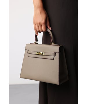 Elevate your everyday ensemble with this Lluvia Top Handle Satchel Mini Tote Bag, a timeless choice for modern elegance. Featuring a structured silhouette and refined grain-textured finish, this handbag blends style and practicality effortlessly. The polished gold-tone turn-lock closure adds a touch of sophistication. Ideal for work or weekend outings, it’s compact yet roomy enough for your essentials. Key Features: • Material: Textured faux leather with contrast stitching • Dimensions: 25cm (L) x 20cm (H) x 11cm (W) • Fastening: Gold-tone turn-lock flap closure • Detail: Minimalist top handle design with structured base and sleek finish 