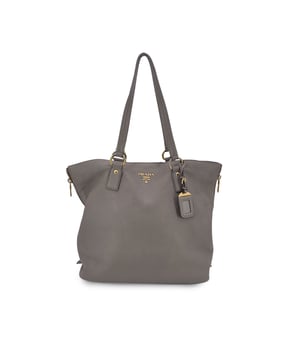 VINTAGE, RRP AS NEW
This beautiful item will come with a Certificate of ity provided by Entrupy. The certificate will be provided at no further cost  Elevate your everyday with this beautiful PRADA tote bag, crafted in luxurious grey taupe textured leather-a timeless neutral that pairs effortlessly with any look. Showcasing PRADA's signature blend of elegance and functionality, this tote features structured double top handles and refined silver-tone Prada lettering on the front, adding a touch of quiet sophistication.  The top opens with a button closure to reveal a spacious main compartment, fully lined in PRADA's iconic jacquard fabric. Inside, you'll find one zip pocket and one open pocket to keep your essentials neatly organized. A 'PRADA Milano' tag and a discreet numbered label tucked inside the interior pocket ensure ity.  Finished with four metal bottom feet for added protection and polish, this tote is as practical as it is chic-perfect for the modern woman who values understated luxury. Condition Rating: B - VERY GOOD CONDITIONCondition Details: Some wear of use on the upper border (please see photos). Some wear of use on the hardware. Please check the photos carefully and ask if you need to know more details or if you have any doubts.Measurements (cm):Depth: 15.2Height: 34.3Length: 36.8Other Details: Dustbag? NoKeys? NoBox? No Measurments:  width: 152 mm length: 368 mm height: 343 mm strap length: 0 mm handle drop: 0 mm