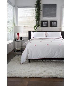 Infuse your bedroom with elegance and subtle romance with the Filigree Hearts Duvet Cover Set. Presented in crisp white and finished with delicately embroidered red hearts, it brings a touch of charm that feels both timeless and contemporary. Crafted from 100% cotton with a smooth 144 thread count, the fabric is soft, breathable, and naturally comfortable for every season. Refined red piping frames the design beautifully, adding a tailored finish that elevates your décor. Available in Single, Double, King, and Super King, this set is designed to combine everyday comfort with lasting style.