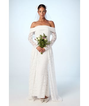 Exquisite lace wedding dress with elegant Bardot neckline showcasing dcolletage beautifully
        Long sheer lace sleeves adding a touch of romance and sophistication
        Innovative removable skirt design offering two stunning bridal looks in one
        Figure-flattering silhouette with a fitted bodice transitioning into a graceful floor-length hem
        Delicate veil included, completing this enchanting bridal ensemble
    
    Transform your wedding day with this versatile Coast bridal gown that truly delivers two distinct looks for your special day. The stunning Bardot neckline frames your shoulders with timeless elegance, while the intricate lace detailing creates a romantic texture throughout. For your ceremony, embrace the dramatic flair of the removable overskirt, creating a magnificent silhouette as you glide down the aisle. Later, detach the skirt to reveal a sleek, contoured dress perfect for dancing the night away at your reception. Style with simple pearl or crystal jewellery to maintain the dress as your focal point, and pair with classic pointed court shoes. The accompanying veil adds the finishing touch to this adaptable gown that celebrates traditional bridal beauty with contemporary practicality.
