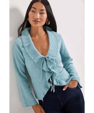 Feminine ruffle detail along the front edges adds a playful touch to this knitted cardigan
        Elegant tie-front closure with a charming bow detail for a customisable fit
        Flattering V-neckline frames the dcolletage beautifully
        Ribbed texture throughout provides visual interest and comfortable stretch
        Wide-cut sleeves with a straight finish offer ease of movement and contemporary styling
    
    This Petite Ruffle Tie Front Cardigan from Dorothy Perkins brings a delightful blend of comfort and femininity to your daywear collection. The soft knitted fabric with added stretch ensures all-day comfort whilst the ruffle detailing and tie-front design create a flattering silhouette that works wonderfully for your frame. Style it as shown with wide-leg denim trousers and neutral flats for a relaxed weekend brunch with friends, or layer over a simple camisole with tailored trousers for family gatherings. The versatile design makes it perfect for the transitional months - simply add a lightweight scarf when there's a chill in the air. This cardigan is an effortless way to add a touch of pretty detailing to your casual ensembles without compromising on comfort.